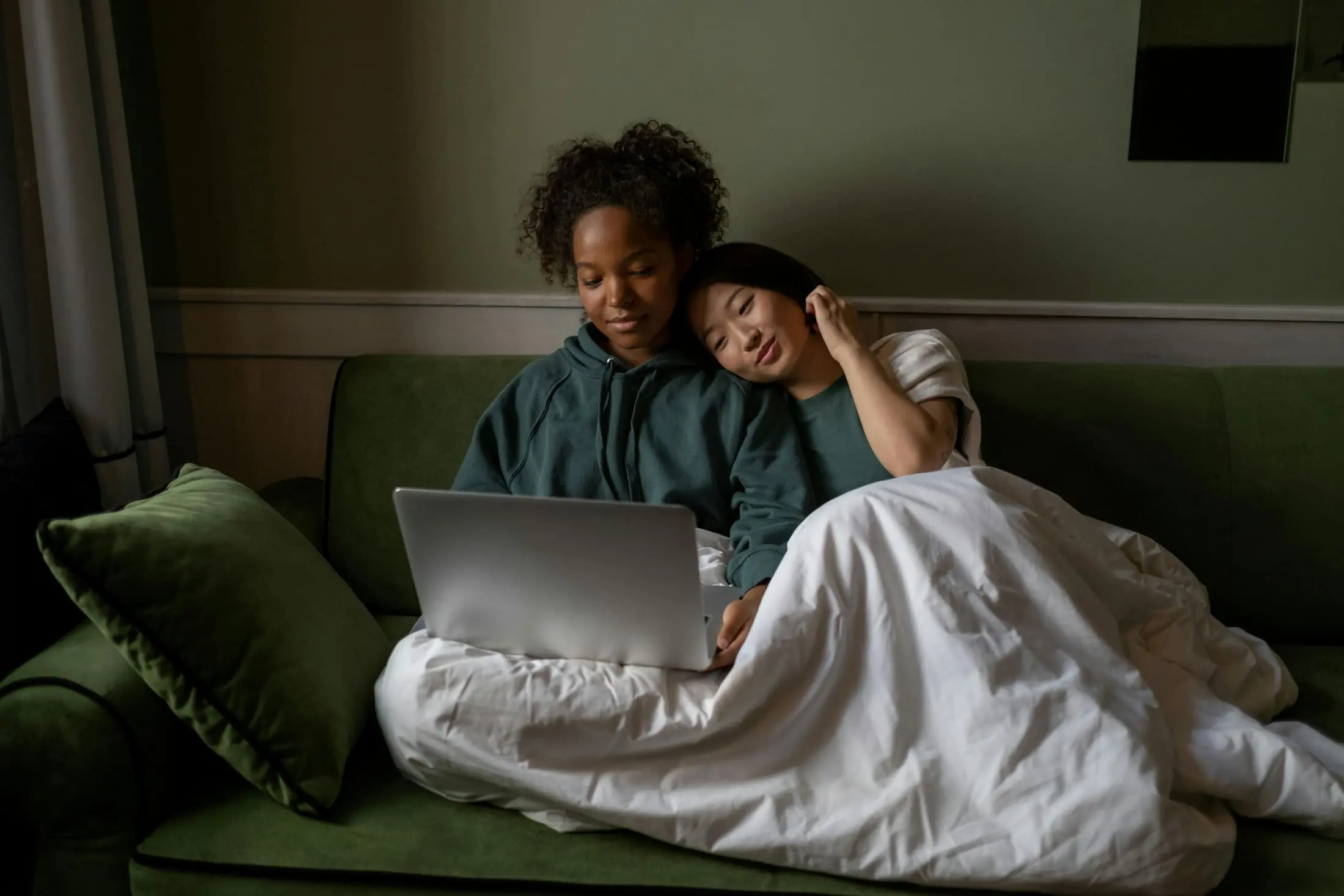 Two people using a laptop together on a couch